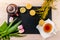 Women& x27;s day greeting card with tulips, mimosa, tea and cupcakes with black stone board on wooden background