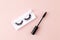 Women`s eyelashes and brush on a pink background. Top view of Mascara brush and long false lashes. Eyelash extension.