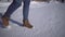 Women`s feet in beige boots walking in the snow