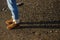 Women`s feet in jeans and brown demi-season suede boots on the beach. Hard sunlight