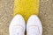 Women`s feet on the road. White sneakers on asphalt top view