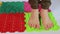 Women`s feet walk on orthopedic multi-colored puzzle mats