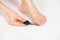 Women& x27;s foot on a white background, removal of rough skin on the big toe with a laser file, pedicure