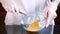 Women`s gloved hands whipping eggs in a transparent bowl