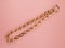 Women`s gold chain necklace on pink shimmering background