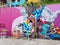 Women`s graffiti on a colorful pink background and some benches, in commune 13