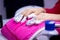 Women`s hand with aluminum foil on nails on pink towel in nail salon