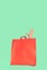 A women`s hand comes out of a red paper shopping bag on a mint green background. Buying and selling, consumer society.