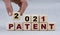 Women`s hand folds wooden cubes with the words 2021 PATENT on a gray background