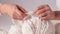 Women\\\'s hands BEAUTIFUL close-up, knitting for a newborn, crochet. top view on soft creamy white background.AI generated