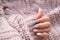 Women`s hands with a beautiful matte oval manicure in a warm knitted sweater. Winter trend, polish beige nails with gel polish,