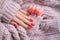 Women\\\'s hands with a beautiful matte oval manicure in a warm pink knitted sweater