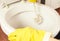 Women`s hands close - up in yellow rubber gloves wash the toilet with brush.