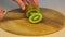Women\\\'s hands cuts with a knife a unpeeled kiwi.