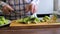 women\'s hands are cutting broccoli on a cutting board. healthy eating. a woman in a shirt. cooking