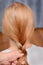 Women`s hands do hairstyle pigtail girl. Close-up rear view