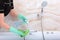 Women`s hands in green rubber gloves clean the faucet on the bath. An unrecognizable photo. The concept of cleanliness and hygien