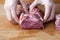 Women`s hands hold a piece of raw beef meat on a wooden background