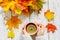 Women`s hands holding a Cup of hot tea with lemon on a white wooden table with colorful autumn leaves