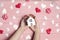 Women`s hands with miniature white toy house with hearts on pink wooden background