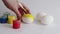 women\\\'s hands paint white eggs with a brush against the background of paint cans and a white background