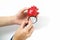 Women`s hands with a red heart and a blue stethoscope on a white background close-up. Heart in hand. Concept of cardiology.