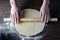 Women`s hands roll out rolling pin dough on a wooden table, side light, Flatley, top view
