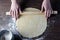 Women`s hands roll out rolling pin dough on a wooden table, side light, Flatley, top view