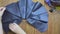 Women's hands show sewing product made of eco-leather on wooden table.