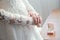 Women`s hands on a white wedding dress. show her wedding ring with box in background.