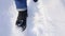 Women`s legs in black boots and blue jeans are walking in the snow. Top front view. Walk in the snowy city.