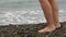 Women`s legs close-up on the background of sea waves, rest on the coast