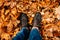 Women\'s legs in dark shoes standing on a yellow fall maple leaves to autumn park