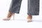 Women& x27;s legs in elegant patent leather high-heeled beige shoes. Gray wide leg jeans. Side view