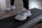 Women`s legs in fashionable white sneakers stand on the steps platform in the gym. Young woman is exercising in a modern gym.