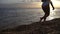 Women's legs and feet walking on the waves of sea water on a sandy beach. A woman walks on the surf in the golden