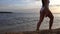 Women's legs and feet walking on the waves of sea water on a sandy beach. A woman walks on the surf in the golden