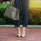 Women`s legs in grey high heels shoes. Bright grey shoes, bag and blue pants. Cotton pants, stylish ladies shoes and bag. Business