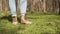 Women`s legs in jeans and boots, walking on the bright green grass.