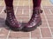 Women`s legs in maroon tights and maroon leather boots with thick soles with high lacing