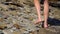 Women\'s legs walk on stones. A tourist walks along sharp steep stones. Walking tour. Female legs standing on a stone on