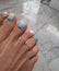 Women\'s pedicure with a pale blue gel polish and white design.