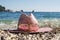 Women`s straw beach hat sunhat with sunglasses lies on the pebble beach, surrounded by round stones on a background of blue sea