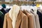 Women's stylish traditional wool coats on hangers in the store. Autumn-winter season in clothes. Brown color