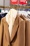 Women's stylish traditional wool coats on hangers in the store. Autumn-winter season in clothes. Brown color