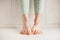 Women`s tired ankles with clasped fingers and bulging veins close-up on a light background.