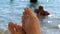 Women`s toes and feet against the background of the sea, the rays of the sun on the waves, beach vacation, summer resort