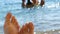 Women`s toes and feet against the background of the sea, the rays of the sun on the waves, beach vacation, summer resort