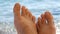 Women`s toes and feet on the background of the sea, the rays of the sun on the waves, beach vacation, summer resort