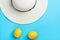 Women`s white straw beach hat ripe organic yellow lemons on mint blue background. Summer vacation fun fashion